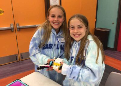 2 girls sharing a robot created in our robotics program.